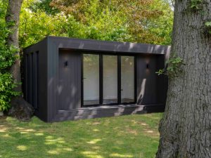 Black Mala Garden Room in leafy garden.